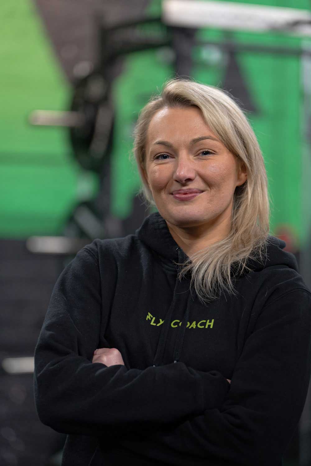 Confident female coach smiling in a gym environment